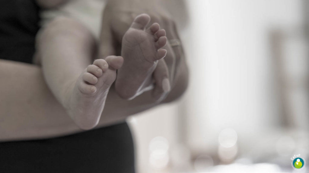 pieds d'un bébé porté contre sa mère