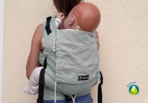 poupon bambin lesté dans un porte-bébé didysnap de didymos au dos pendant une formation au portage des bébés en crèche