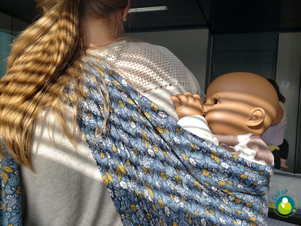 passage au dos d'un poupon avec un écharpe lors d'une formation de monitrice de portage de bébés à Strasbourg