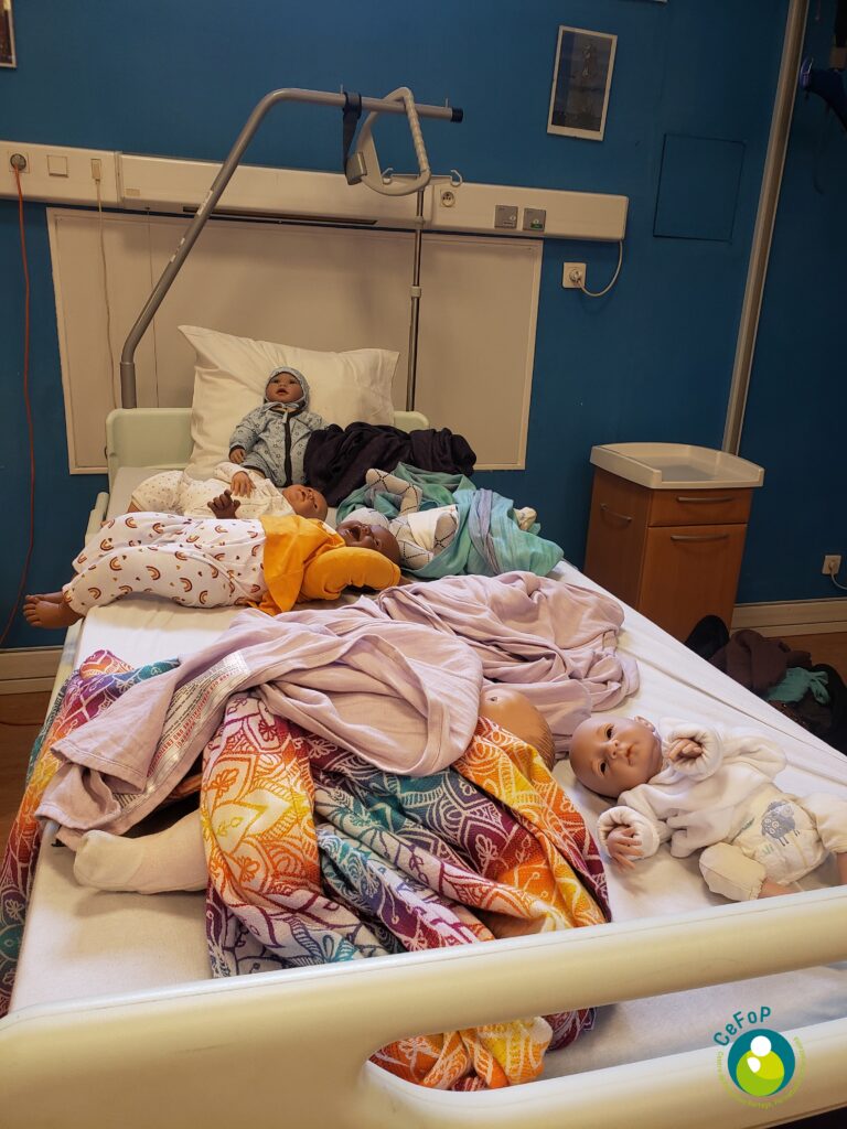poupons lestés et écharpes de portage sur un lit d'hôpital pendant une formation de monitrice de portage de bébés dans un service de néonatologie à paris